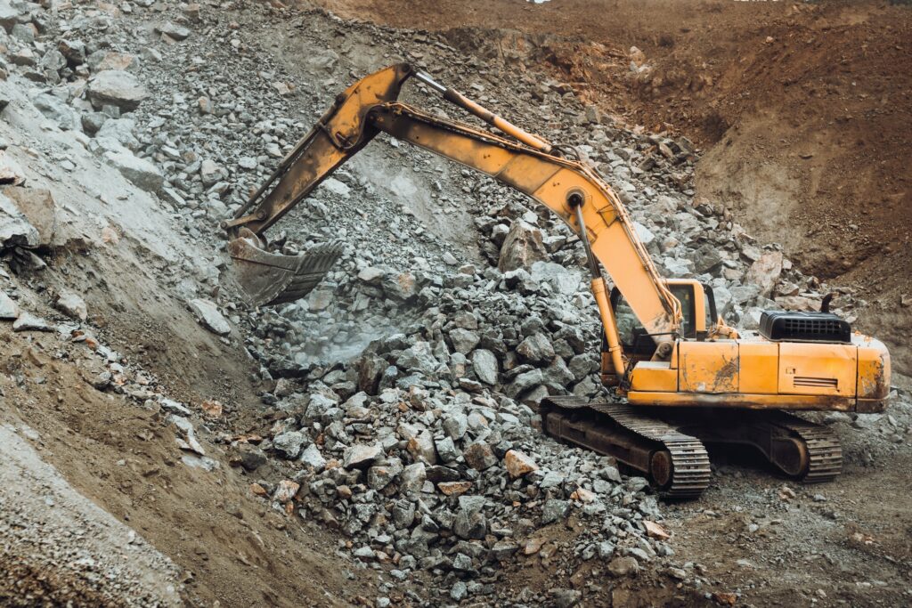 Industrial track type excavator digging at a quarry or a construction site, machinery details